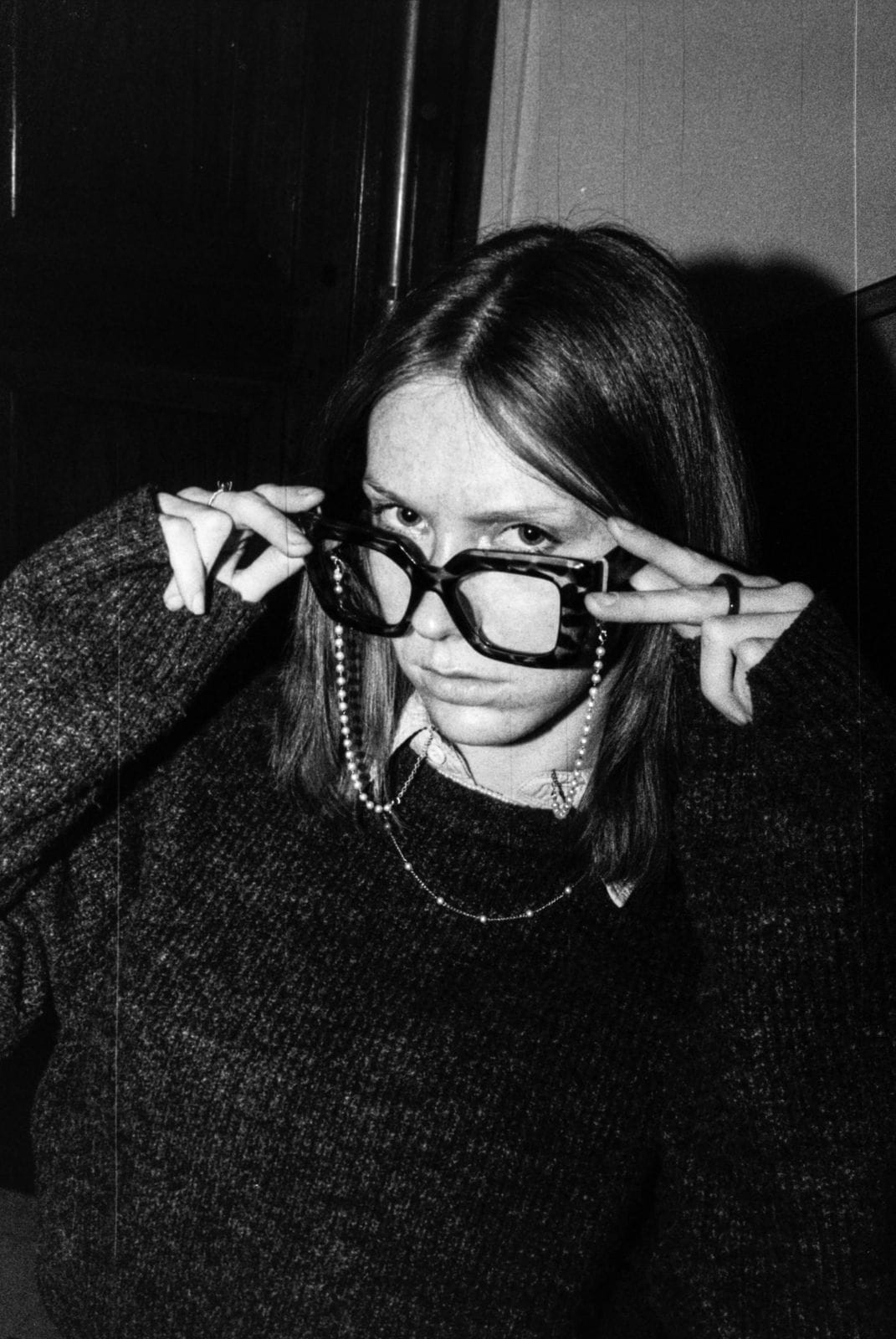 Personne abaissant ses grosses lunettes, regard par-dessus la monture.